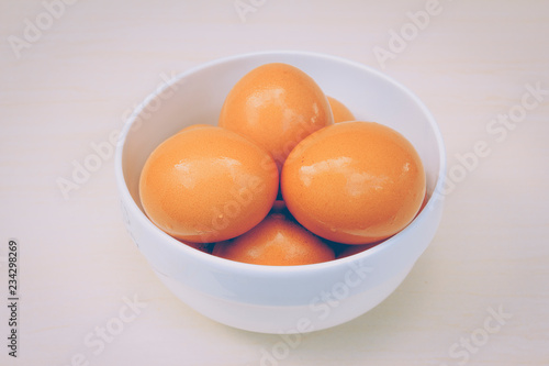 Fresh red eggs inside a white bowl.