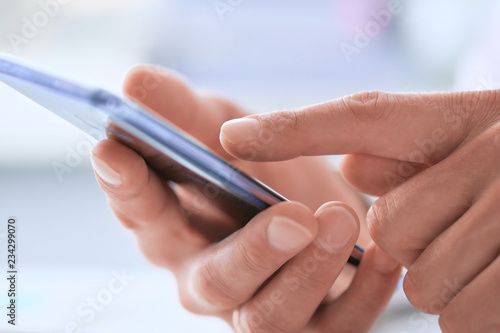 Businessman using smart phone in office close up.