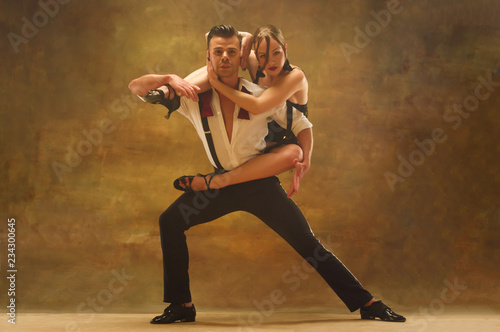 Flexible young modern couple dancing tango in studio. Fashion portrait of attractive dancing couple. Man and woman. Passion. Love. perfect skin facial and make-up. Human emotions - love and passion