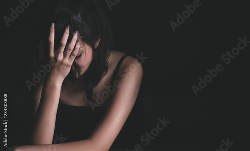 Sad depressed woman suffering from family life. women sitting in dark room and right palm touching her face feeling worry. Young beautiful women thinking how to solve problem.