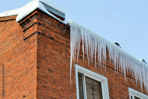 Long, big and dangerous icicles on a brick house roof