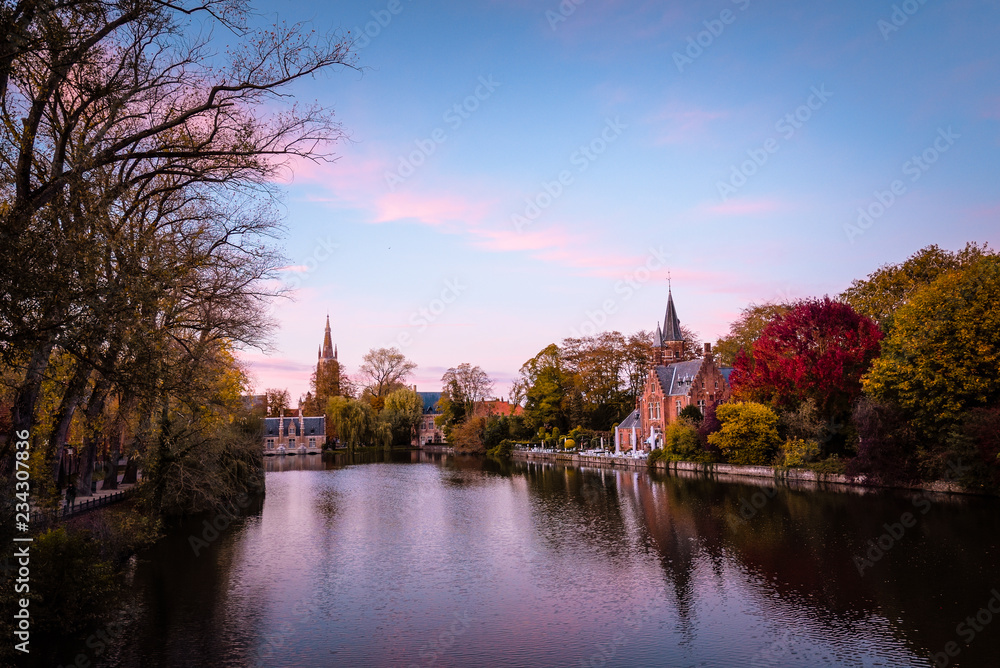 Colorful view of Brugge canal during autumn season, Castel architecture on river side under sunset light. Belgium