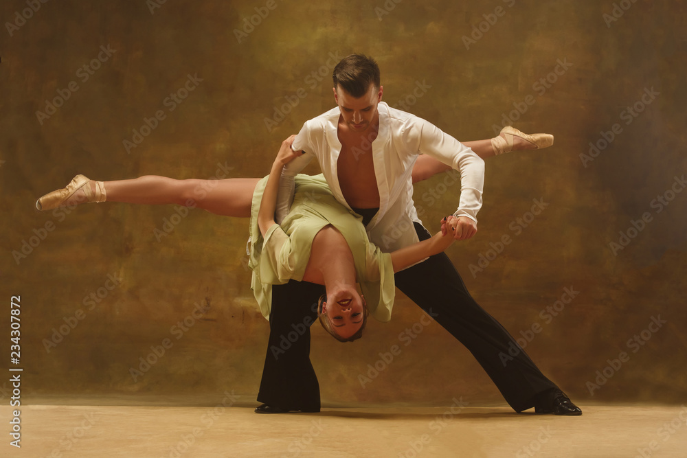 Flexible young modern couple dancing tango in studio. Fashion portrait of attractive dancing couple. Man and woman. Passion. Love. perfect skin facial and make-up. Human emotions - love and passion