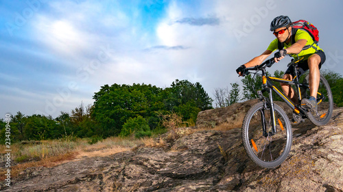 Fototapeta Naklejka Na Ścianę i Meble -  Cyclist Riding the Bike on Rocky Trail at Sunset. Extreme Sport and Enduro Biking Concept.