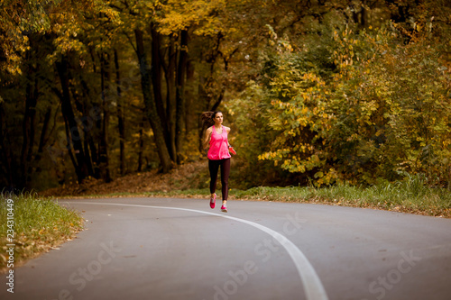 Young fitness woman running at forest trail