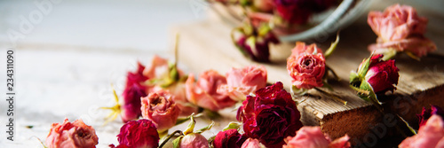 Buds of dry roses in glass bottle on jute background