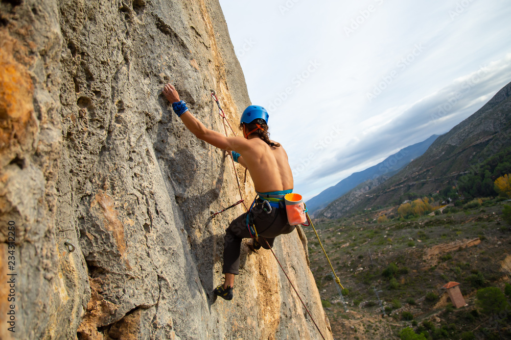 Shirtless climber man climbing mountain wall on amazing sunny day 