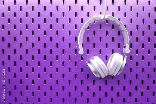 White headphones on wooden pegboard background with various concept colour