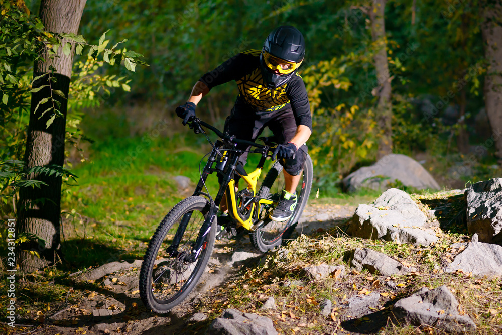 Professional Cyclist Riding the Mountain Bike on Autumn Forest Trail. Extreme Sport and Enduro Cycling Concept.