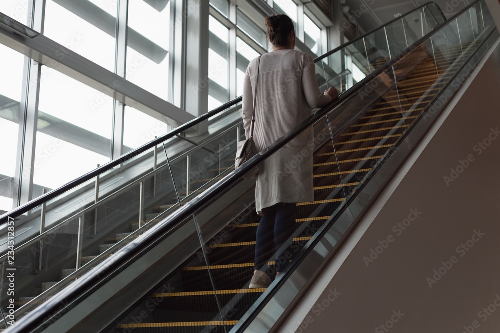 Woman moving up on escalator at railway station Woman moving up on escalator at railway station