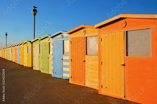 A row of twenty colorful beach huts with a diminishing perspective on Seaford Promenade, Sussex, UK © Gill