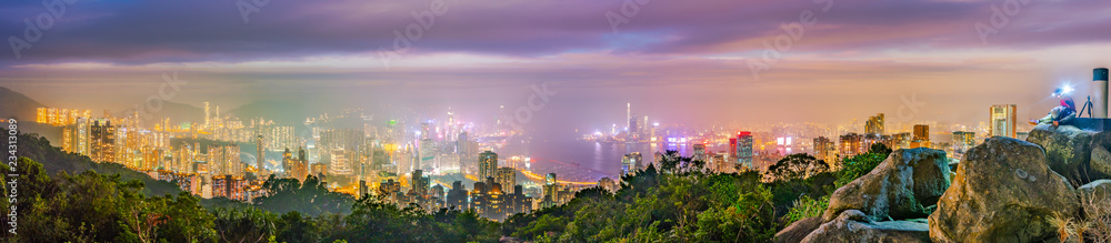 Hong Kong night panorama wide view of Victoria Harbour skyline from Red incense burner summit,Misty night.