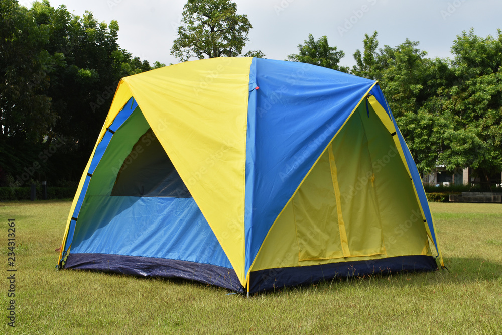 Camping tent setup on green field at front of house.