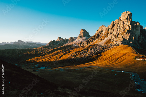 silent quiet peaceful view of grand rocky canyon in dolomites valley at sunset with clear blue sky and yellow meadows