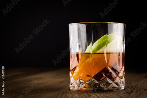 Whiskey with Slices of Green Apple on Wooden Table and black background. Copy Space
