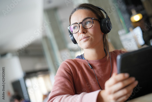  Young woman inside an urban space with headphones and devices