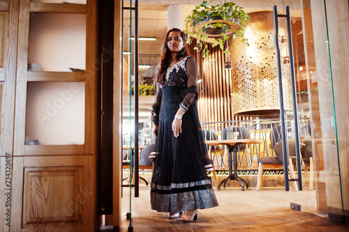 Pretty indian girl in black saree dress posed at restaurant.