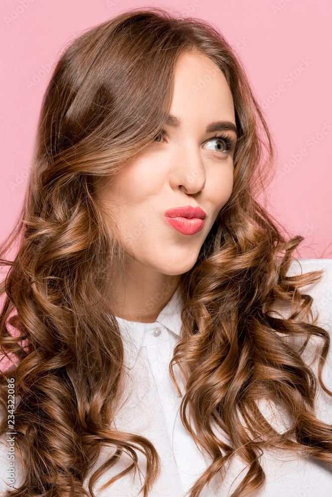 I kiss you. Portrait of attractive woman with kiss on lips. Pink studio. Beautiful female portrait. Young happy emotional funny woman looking at camera. Human facial emotions concept. Trendy colors