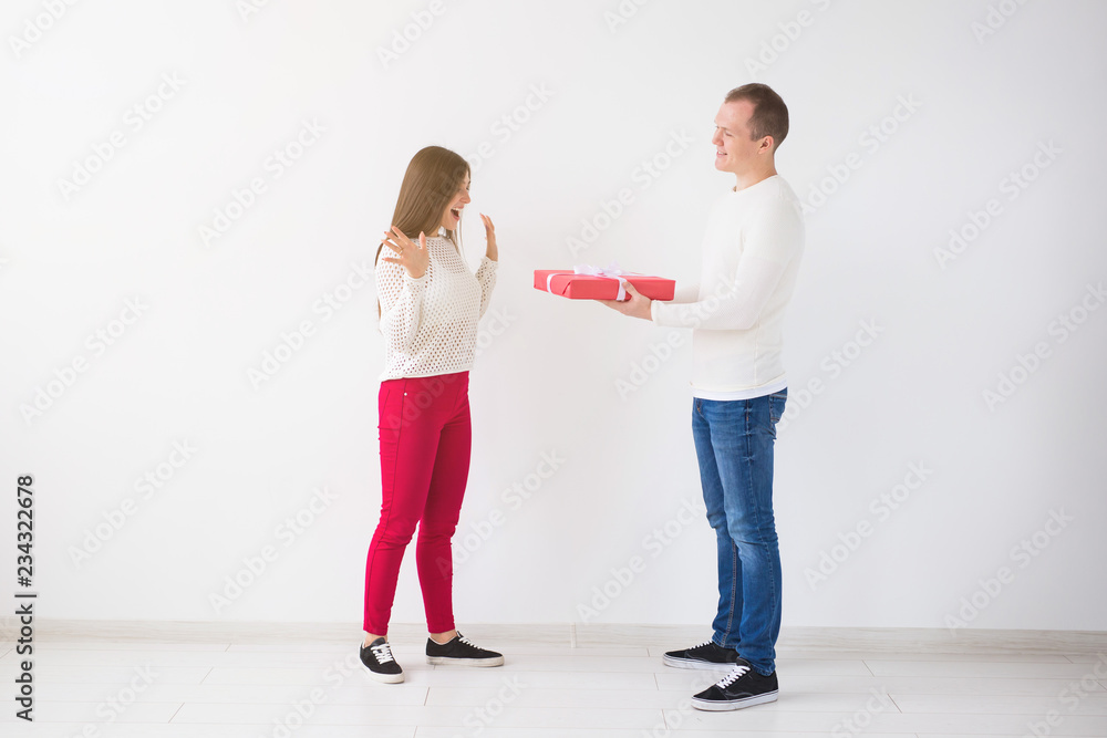 People, christmas, birthday, holidays and valentine's day concept - Handsome man is giving his girlfriend a gift box on white background People, christmas, birthday, holidays and valentine's day concept - Handsome man is giving his girlfriend a gift box on white background