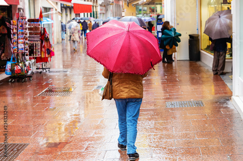 people with umbrellas in a shopping street on a rainy day