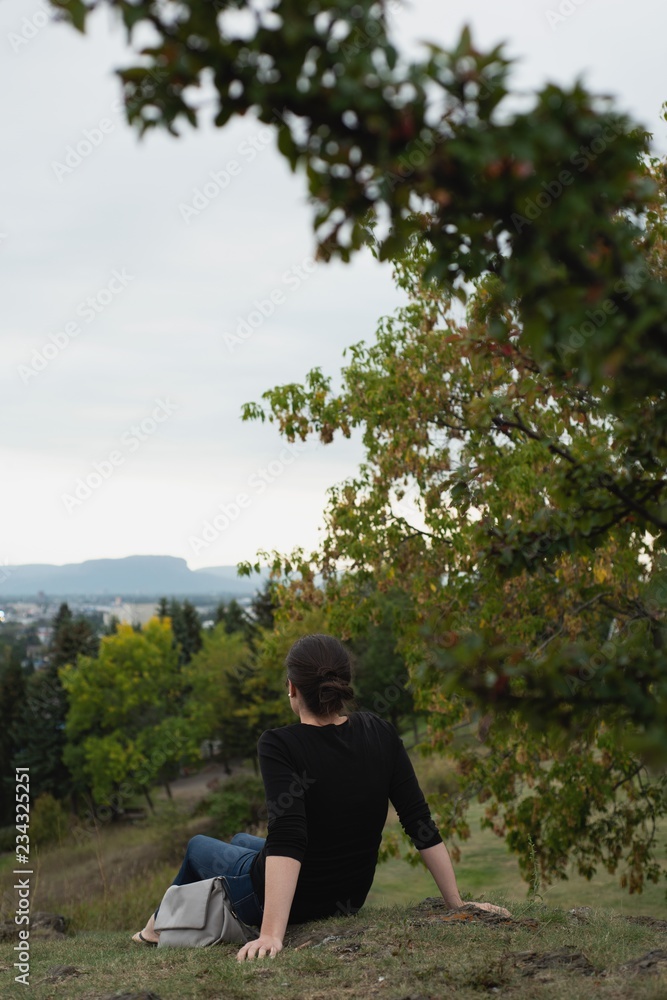 Woman sitting on hill and looking at view Woman sitting on hill and looking at view