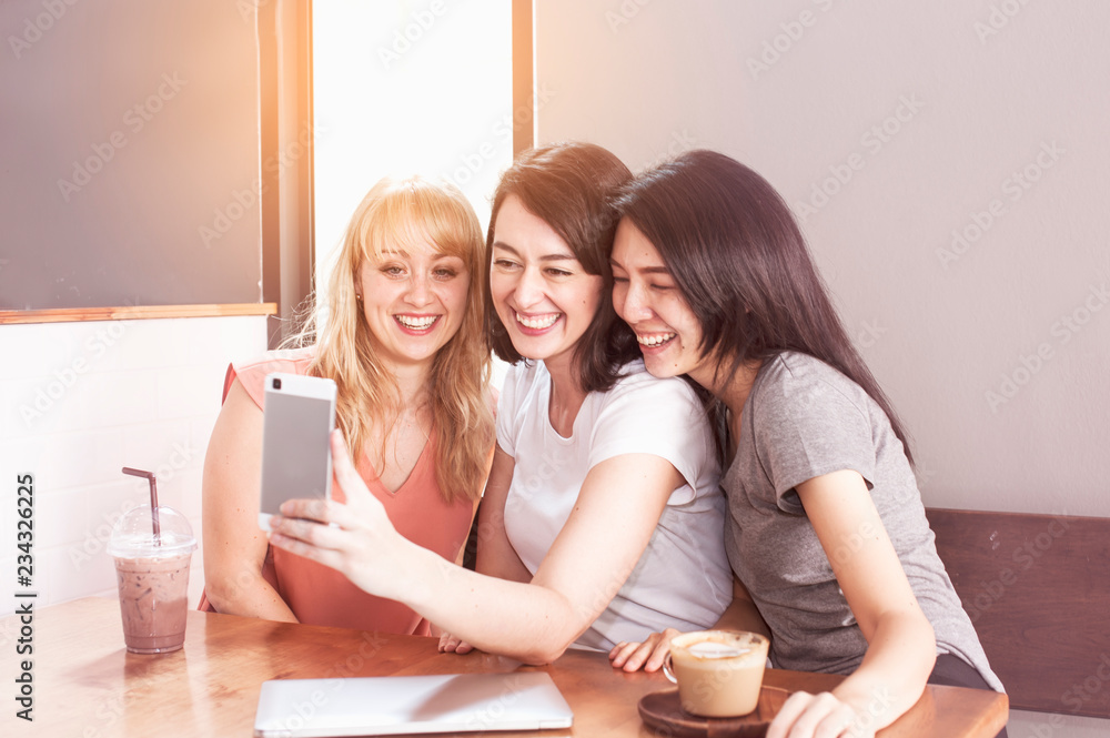 Three happy multi nation girlfriends team making selfie and smiling while relaxing in cafe.lifestyle and relax time concept. Three happy multi nation girlfriends team making selfie and smiling while relaxing in cafe.lifestyle and relax time concept.