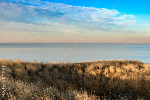 Stunning view over  grass covered dunes towards the of the sea horizon.