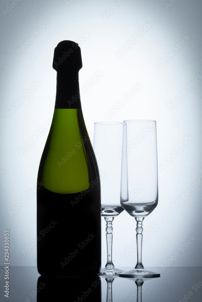 Botella de vino con copas de champaña a contraluz Botella de vino con copas de champaña a contraluz