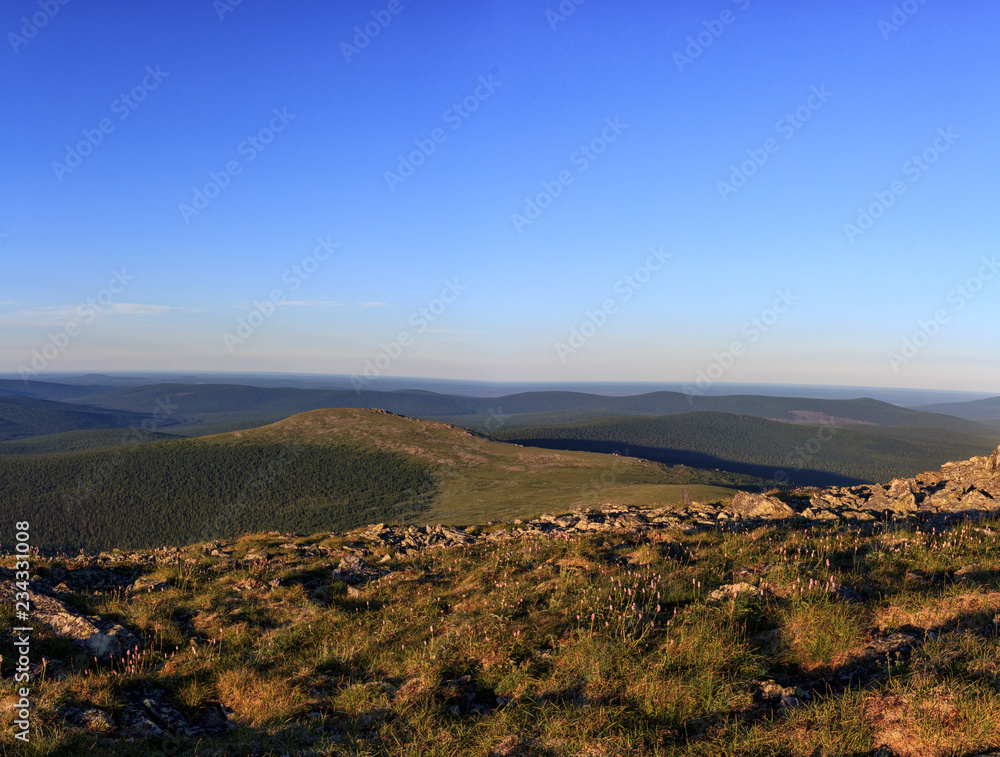 Mountain valley of the Northern Urals in summer. Traveling in the Northern Urals. Beautiful panorama of mountain valleys and passes and a blue sky. Mountain valley of the Northern Urals in summer. Traveling in the Northern Urals. Beautiful panorama of mountain valleys and passes and a blue sky.