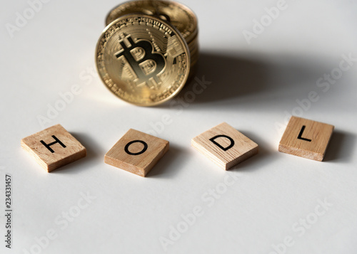 Bitcoin with letter tiles using a popular slang term "hodl" deliberately misspelled in trader jargon, low angle on white.