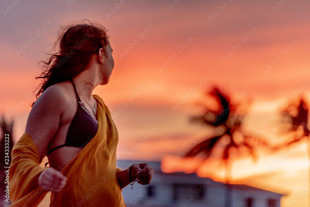 Beautiful young bikini woman in tropical sunset