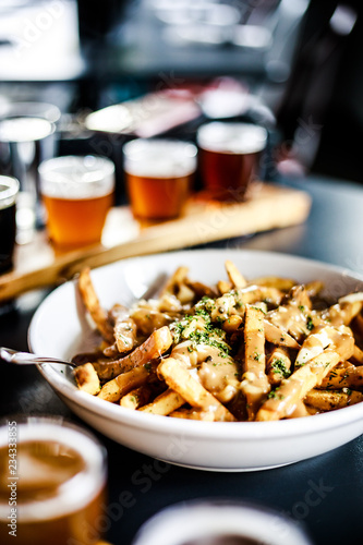 Bowl of poutine with pint glasses photo