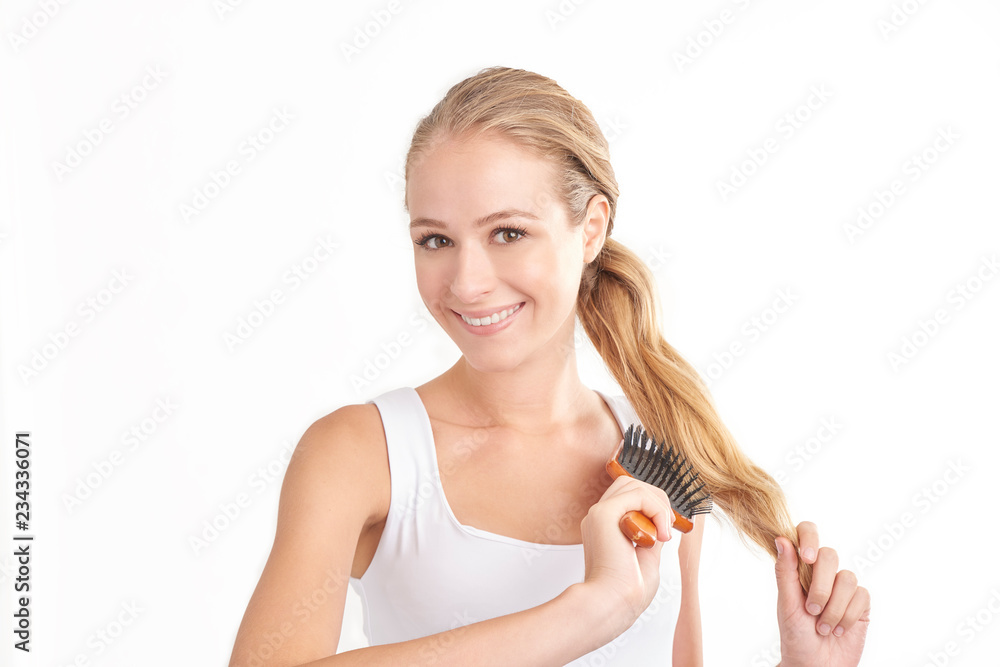 Portrait of beautiful young woman standing at isolated white background while brushing her hair. Portrait of beautiful young woman standing at isolated white background while brushing her hair.