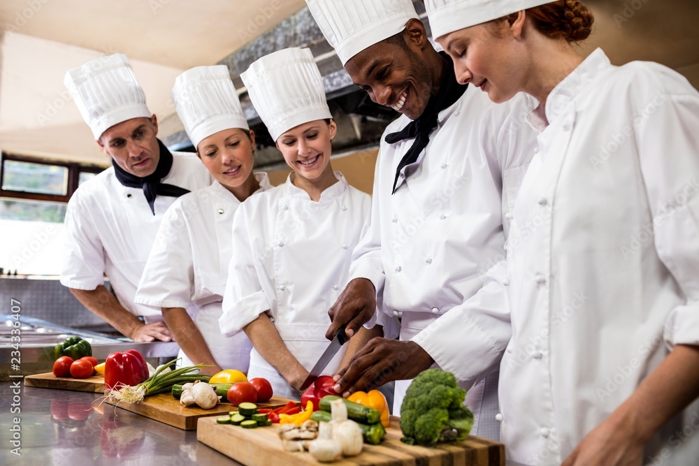 Head chef teaching his team to chopping vegetable Head chef teaching his team to chopping vegetable