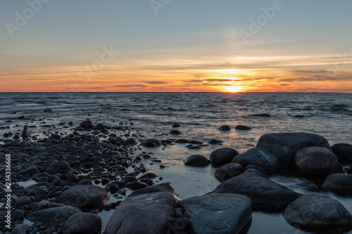 A colourful sunset by the sea with a rocky beach in the foreground