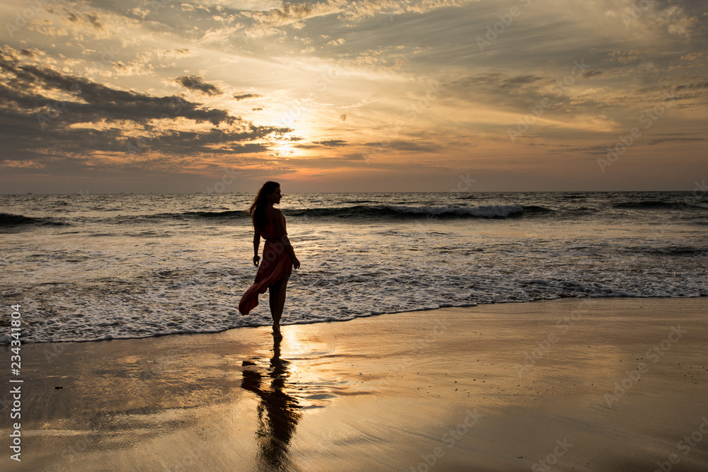 Φωτογραφία Silhouette of a young woman at an incredible sunset in cloudy weather by the sea
