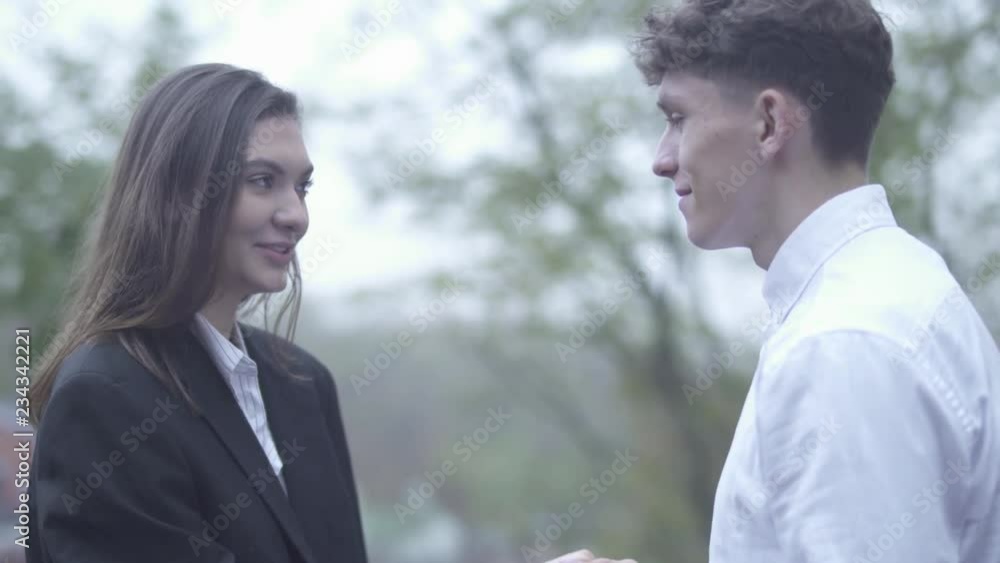 Curly male is kissing hand of female outdoors Young couple spends time together Couple in love Happy couple Curly male is kissing hand of female outdoors Young couple spends time together Couple in love Happy couple