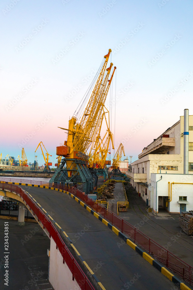 Cargo port with cranes for lifting containers at sunset