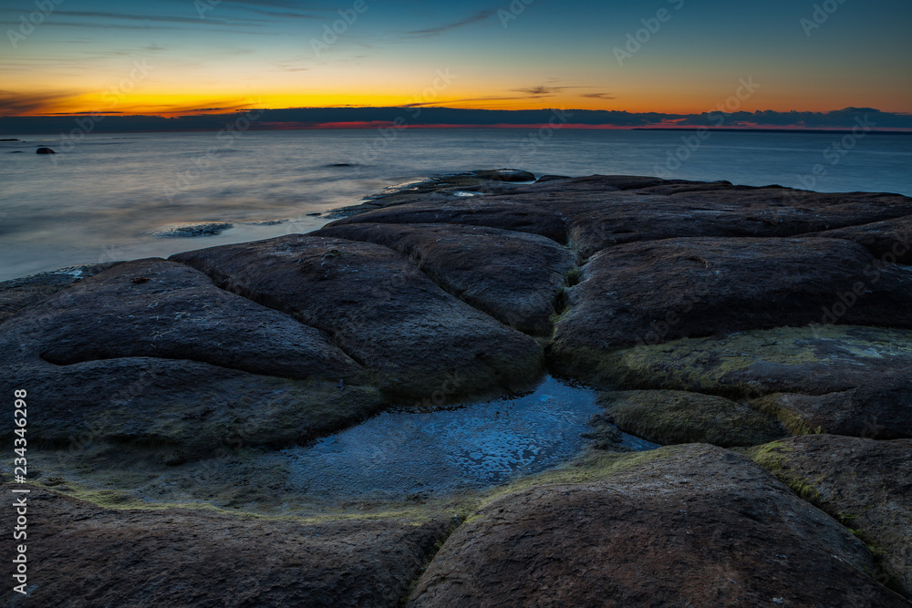 Mystic flat rock laying in the sea. Nightscape after sunset.