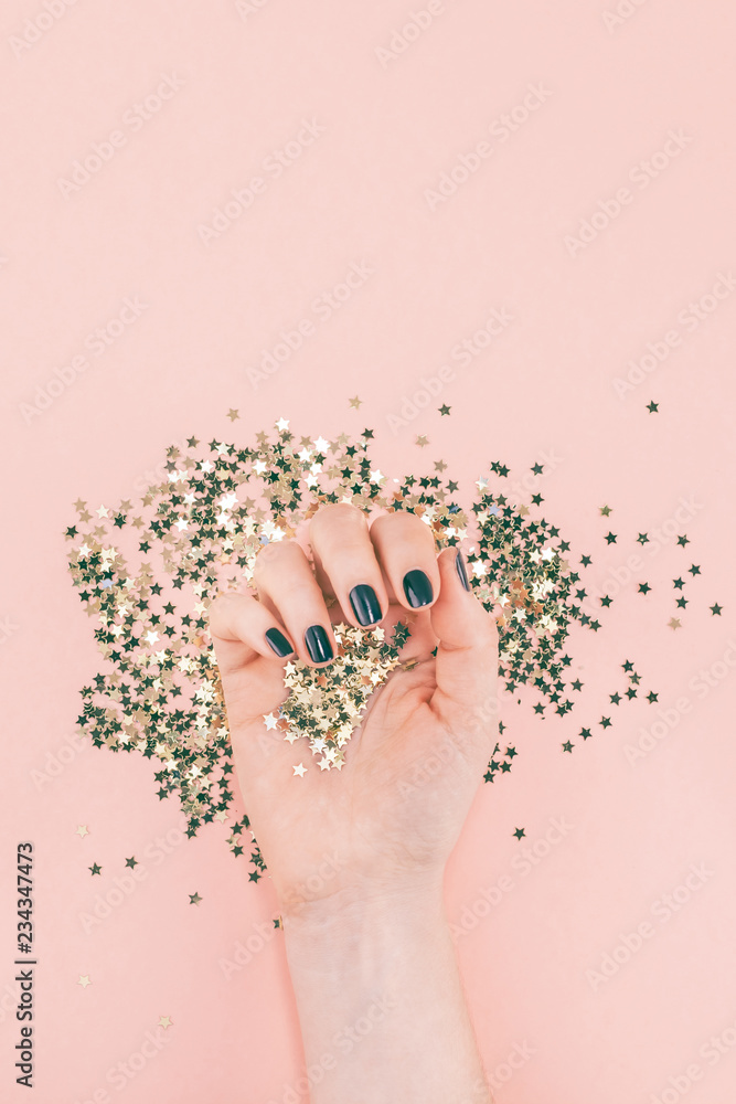 Woman hands covered golden stars confetti on pink Woman hands covered golden stars confetti on pink