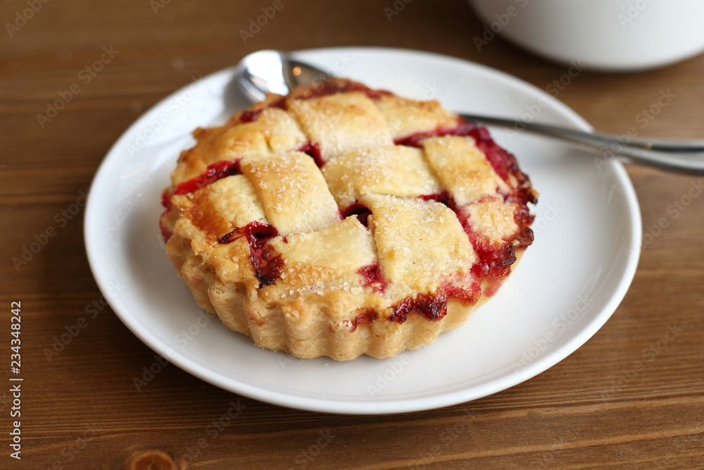 Home made cherry pie with lattice and metal spoon on the white plate and cup of coffee americano on the wooden table Home made cherry pie with lattice and metal spoon on the white plate and cup of coffee americano on the wooden table