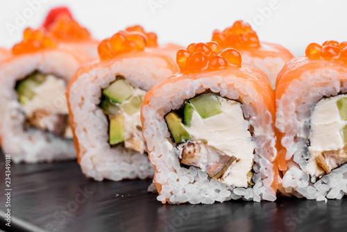 Maki Sushi set on dark pattern background. Sushi Set nigiri, rolls and sashimi served in black square plate