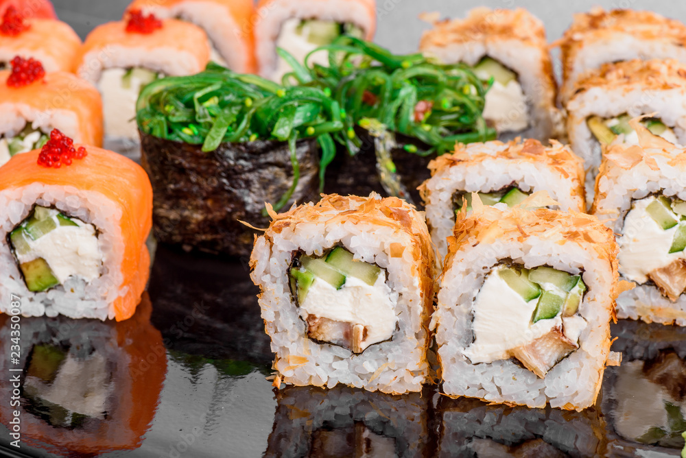 Maki Sushi set on dark pattern background. Sushi Set nigiri, rolls and sashimi served in black square plate Maki Sushi set on dark pattern background. Sushi Set nigiri, rolls and sashimi served in black square plate