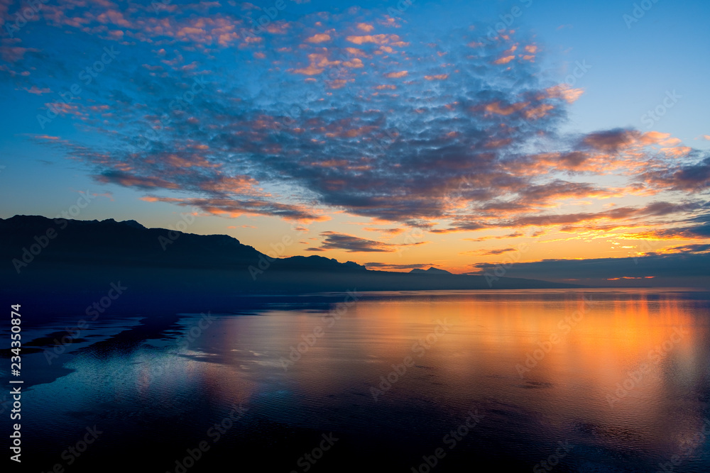 Fototapeta premium Beautiful colorful sunset in the autumn above the French Alps and Lake Geneva where the colors and clouds reflect beautifully.