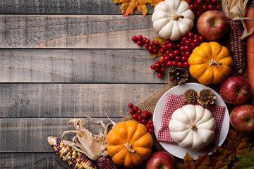 Top view of  Autumn maple leaves with Pumpkin, apple, corn and red berries on old wooden background. Thanksgiving day concept.