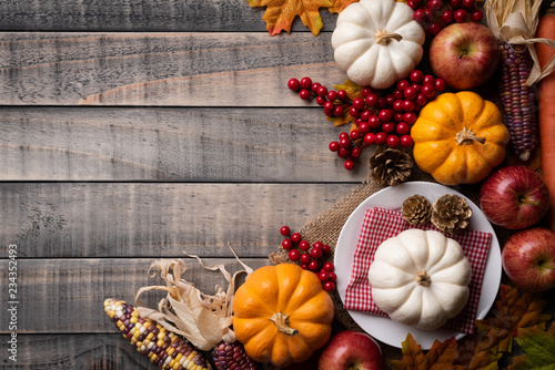 Fototapeta Naklejka Na Ścianę i Meble -  Top view of  Autumn maple leaves with Pumpkin, apple, corn and red berries on old wooden background. Thanksgiving day concept.