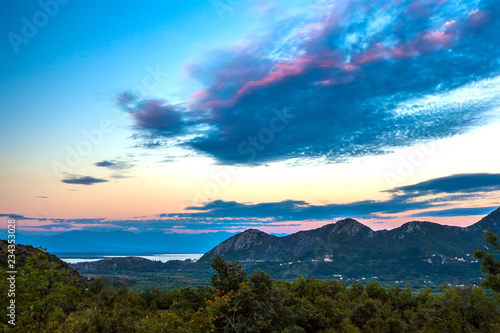 View of the coastal valley of the lake at dusk in the evening with poor lighting  beautiful green mountains under large blue clouds in the sky. Skadar Lake  Podgorica region  Montenegro.