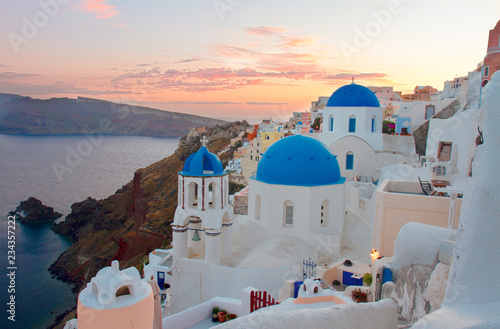 townscape of Oia, traditional greek village of Santorini, with blue domes of churches at sunset, Greece