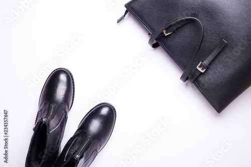 Woman accessory. Black stylish boots, black luxury leather bag on white background. Top view background. Flat lay. Copy space.