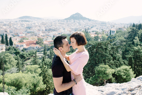 couple have a date on the peak of the hill with panorama view on the city kissing each other